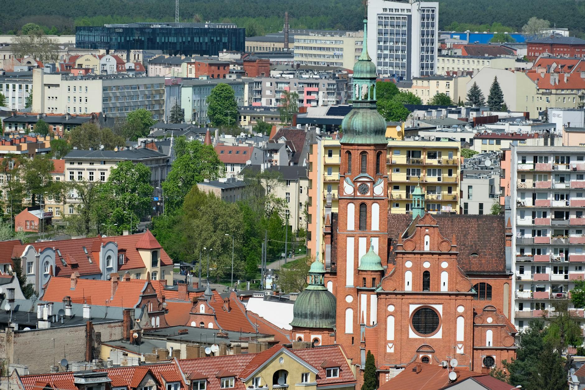 Symboliczna grafika przedstawiająca Ziemię otoczoną zielonymi liśćmi i dłońmi troszczącymi się o nią, z widokiem na miasto Legnica w tle.